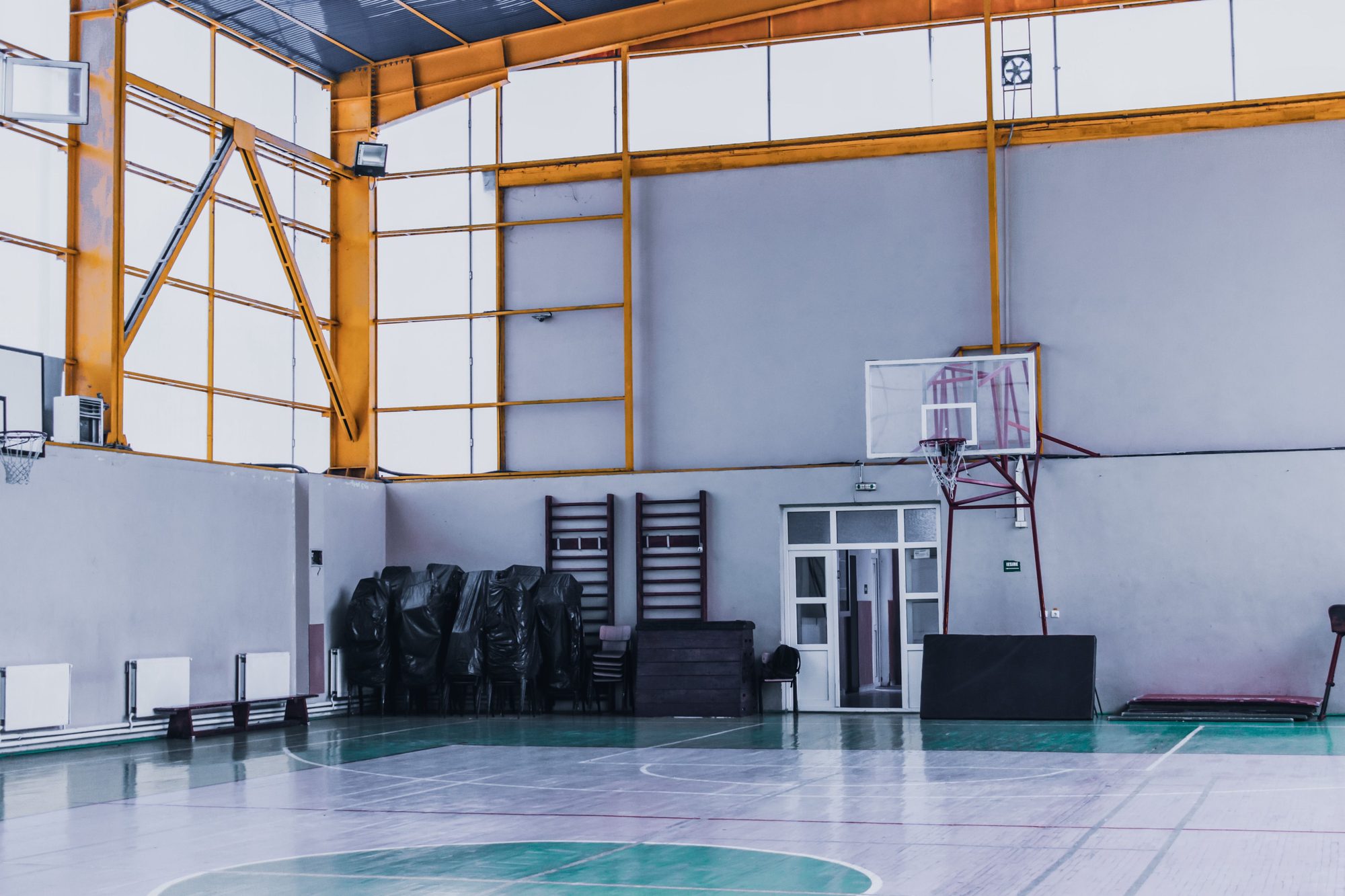 Empty multi-purpose training court with a basketball hoop and wall bars at Threshold Strength Co.