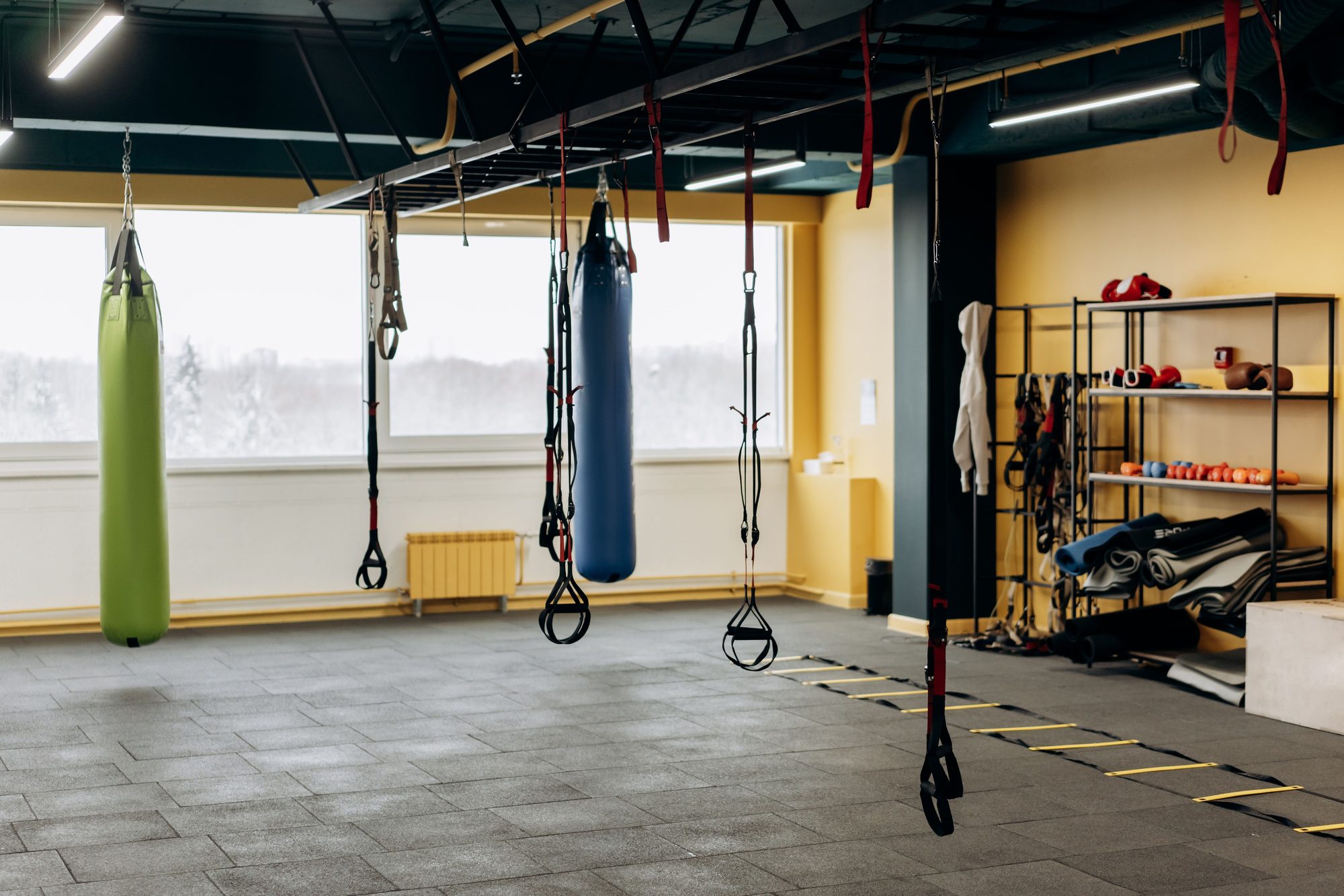 Functional training zone with hanging punching bags, suspension trainers, and kettlebells at Threshold Strength Co.