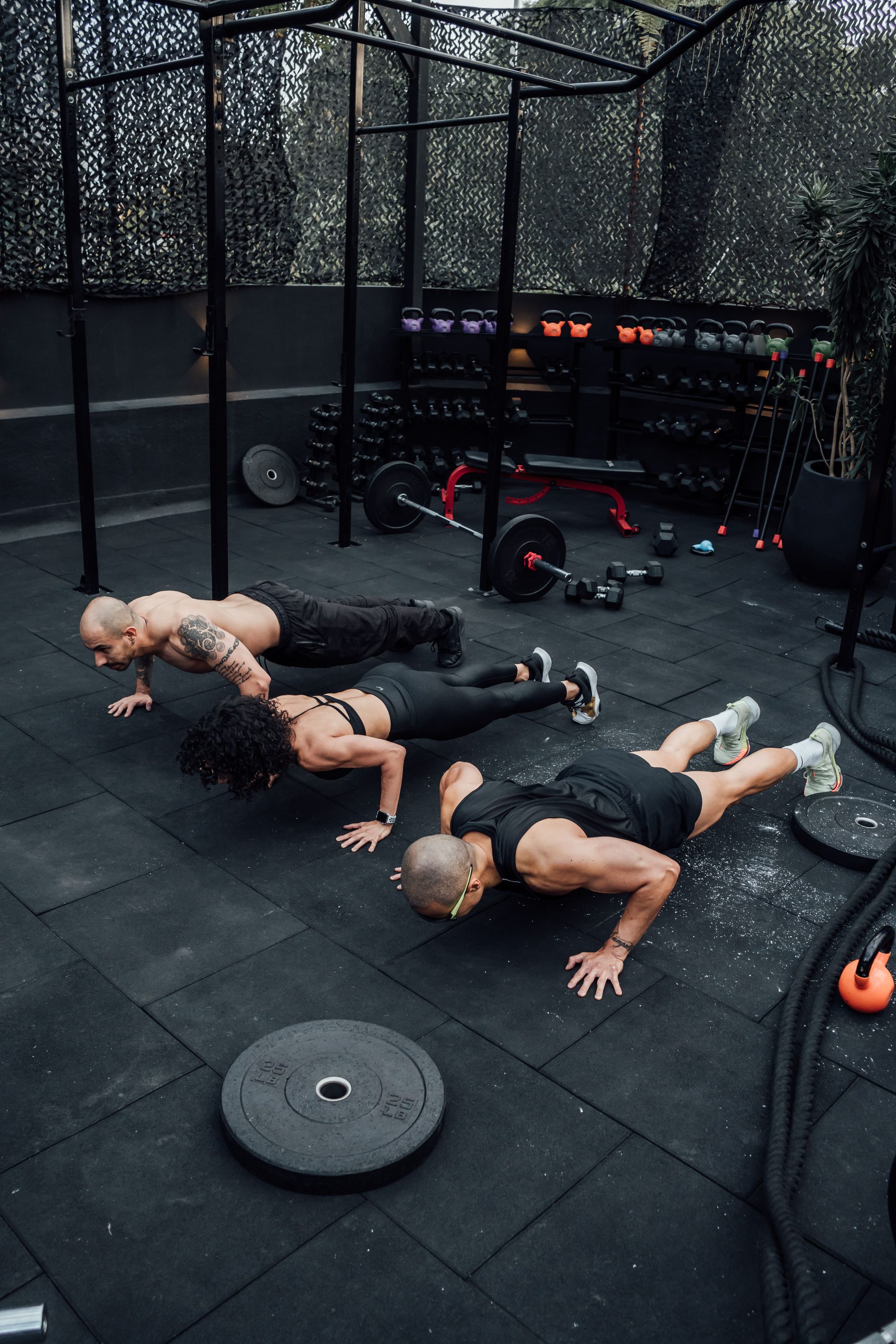 Three athletes performing push-ups together during an outdoor group training session at Threshold Strength Co.
